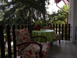 a table and chairs on a porch with a table and a fence at Krisztinusz Vendégház in Fonyód