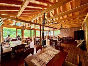 a large room with wooden ceilings and tables and chairs at - Cemi Rooms - River View & Traditional Restaurant in Tamarë