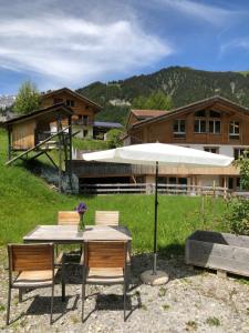 a table with chairs and an umbrella in front of a house at 2-Zimmer Ferienwohnung,Parterre,Sitzplatz,Garage in Adelboden