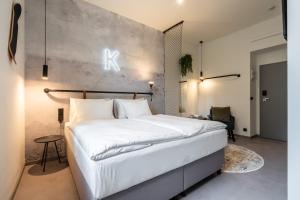 a bedroom with a white bed and a concrete wall at HONEST Karlin in Prague