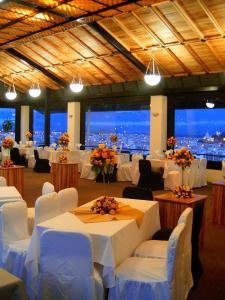 un salón de banquetes con mesas blancas, sillas y luces en Hotel Zeus, en Riobamba