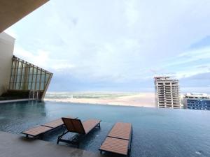 a swimming pool with two chairs and a beach at The PeAk Residence, Multi-Apartment by Emma in Phnom Penh