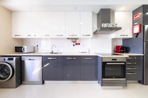 une cuisine avec des armoires blanches et une laveuse et une sécheuse dans l'établissement Baleal Deluxe Apartments, à Baleal