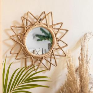 a wicker sunburst mirror hanging on a wall at Saanvi Farmhouse in Hampi