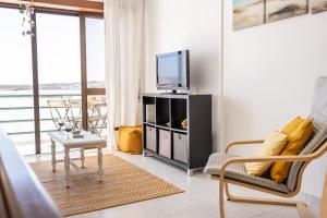 ein Wohnzimmer mit Fernseher und Tisch in der Unterkunft Baía - by Smarthomes in São Martinho do Porto