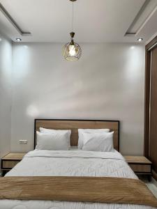 a bedroom with a bed with white walls and a chandelier at Oualidia city in Oualidia