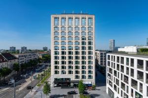 ein hohes weißes Gebäude mitten in einer Stadt in der Unterkunft Andaz Munich Schwabinger Tor, By Hyatt in München