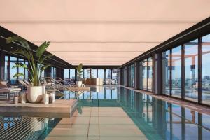 einen Pool in einem Gebäude mit Glasfenstern in der Unterkunft Andaz Munich Schwabinger Tor, By Hyatt in München