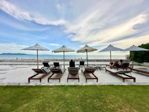 a group of chairs and umbrellas on the beach at Veranda Residence Jomtien Beach Pattaya in Na Jomtien