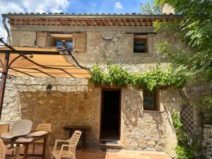 a stone house with a table and chairs and an umbrella at Camping White Rock in Castellane