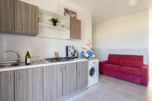 a kitchen with a washing machine and a red couch at Appartamento Fronte Mare in Marina di Strongoli +2 photos