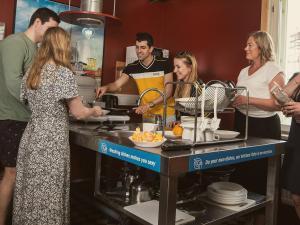 a group of people standing in a kitchen preparing food at Eurohostel in Helsinki