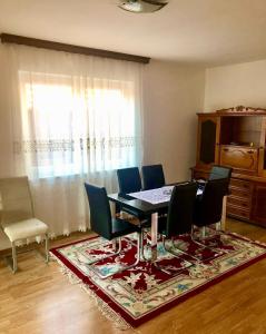ein Esszimmer mit Tisch und Stühlen und einem Fenster in der Unterkunft Apartment Panonija in Tuzla + 7 Fotos