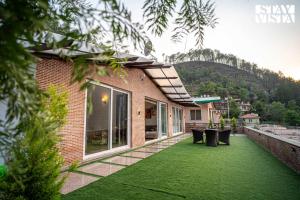 Una casa con un césped verde delante de ella. en StayVista at Suri Ville with Heater & Mountain View, en Bhimtal