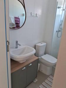 a bathroom with a sink and a toilet and a mirror at Loft decorado e equipado no Centro de Itajaí-SC in Itajaí