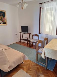 - un salon avec une table et un bureau avec un ordinateur dans l'établissement Apartman Ksenija, à Lun