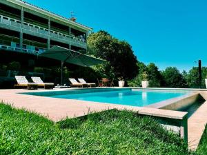 a swimming pool with chairs and an umbrella next to a building at Quinta Escondida da Avessadas in Avessadas