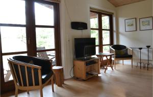 a living room with a tv and chairs and windows at Holiday Home Nybyvej Fanø Vi in Fanø +13 photos