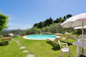 una piscina in un cortile con sedie e ombrellone di Casa Vacanze con piscina a San Gimignano a San Gimignano