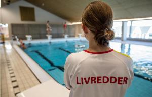 a woman standing in front of a swimming pool at Hytte 16 in Thyborøn