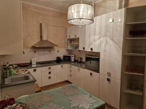 a kitchen with white cabinets and a chandelier at Appartamenti INCORONATA in Lodi