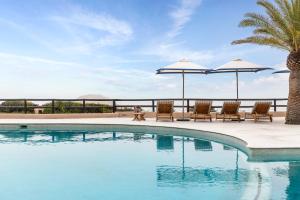 - une piscine avec des chaises longues et des parasols dans l'établissement Vilalara Grand Hotel Algarve, à Armação de Pêra
