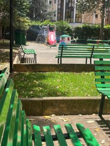 Un parque con bancos verdes y una zona de juegos infantiles. en Claudio House Palermo, en Palermo