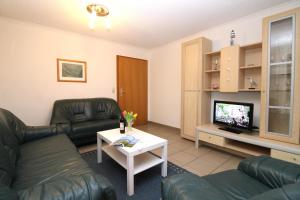 ein Wohnzimmer mit 2 Ledersofas und einem TV in der Unterkunft Ferienanlage Dröse, Haus 8a - Fewo 8 rolli-gerecht in Fulgen