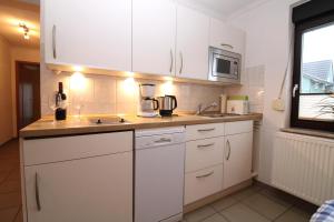 eine Küche mit weißen Schränken und einem Mixer auf der Theke in der Unterkunft Ferienanlage Dröse, Haus 8a - Fewo 8 rolli-gerecht in Fulgen