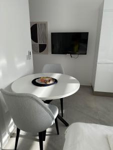 einen weißen Tisch und Stühle in einem Zimmer mit einem TV in der Unterkunft Студия в комплексе Thalassa с видом на горы in Elea