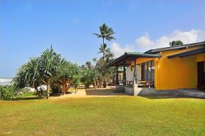 a yellow house with a palm tree behind it at The Beach Cabanas Retreat & Spa in Koggala