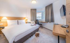 a hotel room with a large bed and a desk at Heart Hotel Grischuna in Sankt Anton am Arlberg