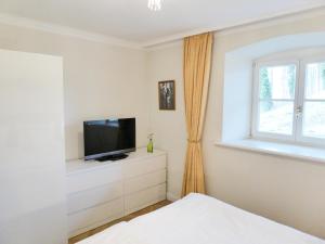 a bedroom with a tv on a dresser and a window at Jagdschloß zu Hohen Niendorf Fewo 1 ELEONORE in Hohen Niendorf