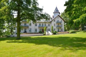 a large white house with a tree in the yard at Jagdschloß zu Hohen Niendorf Fewo 4 in Hohen Niendorf +24 photos