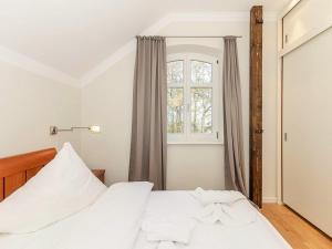 a bedroom with a white bed and a window at Jagdschloß zu Hohen Niendorf Fewo 21 in Hohen Niendorf