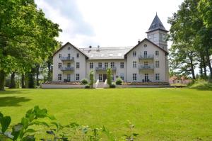 a large white house with a grass field at Jagdschloß zu Hohen Niendorf Fewo 7 in Hohen Niendorf