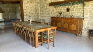 a wooden table and chairs in a room with a stone wall at Maison en pleine nature proche plage Omaha Beach! in Mandeville-en-Bessin +7 photos