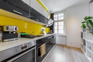 una cocina con paredes amarillas y electrodomésticos de acero inoxidable en Stylish Centre Apartment TGM, en Karlovy Vary 12 fotos más