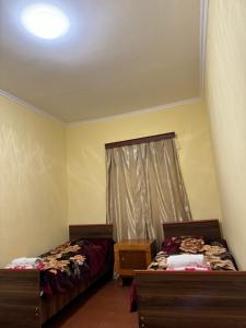 two beds sitting in a room with a window at Vodo's Guesthouse in Chvabiani