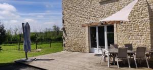 a wooden deck with a table and an umbrella at Maison en pleine nature proche plage Omaha Beach! in Mandeville-en-Bessin
