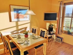 a dining room with a table and chairs and a television at Appartementanlage Am Grün 13 in Wittenbeck