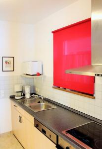 a kitchen with a sink and a red window at Appartementanlage Am Grün 13 in Wittenbeck +17 photos