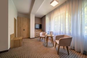 a hotel room with a table and chairs and a window at Medical Sensus in Polanica-Zdrój