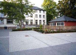 a large white house with a red garage in front of it at Hotel am Ceresplatz in Manderscheid