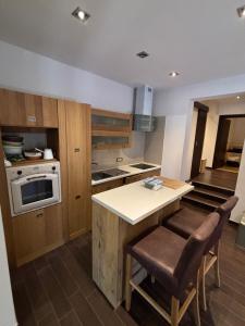 a kitchen with wooden cabinets and a counter with chairs at Apartment Verano in Njivice
