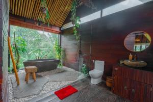 a bathroom with a tub and a toilet and a sink at Let's Get Lost Ubud in Ubud