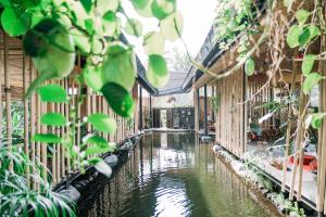 a canal in a greenhouse with plants at Let's Get Lost Ubud in Ubud