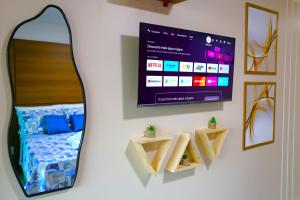 a room with a mirror and a tv on a wall at Rooftop103-Tamandaré in Tamandaré
