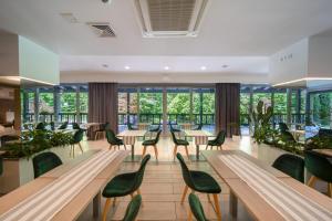a restaurant with green chairs and tables and windows at Medical Sensus in Polanica-Zdrój