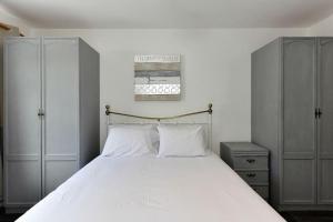 a bedroom with a large bed with white sheets and cabinets at Host & Stay - Oxford Street House in Swansea